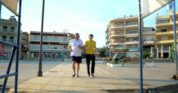 Vater und Sohn joggen mit Kopfhörern in Kurstadt — Stockvideo