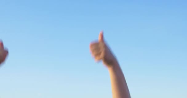 Руки с поднятыми большими пальцами на фоне голубого неба — стоковое видео