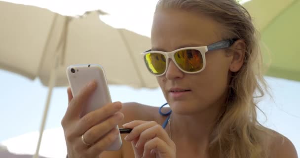 Femme en lunettes de soleil utilisant cellule sur la plage — Video