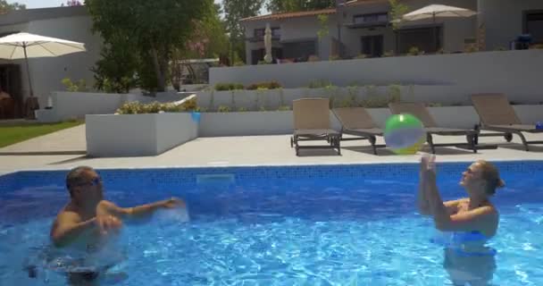 Homem e mulher jogando bola na piscina — Vídeo de Stock