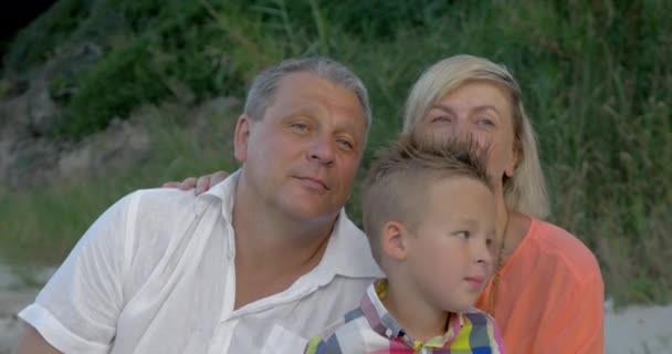 Petit-fils chatouiller grand-père cou tandis que assis sur la plage — Video