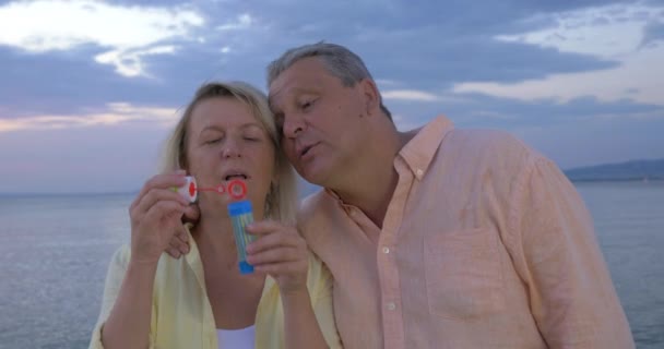 在海岸上吹泡泡的成熟夫妇 — 图库视频影像