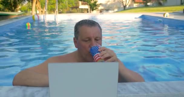 Lächelnder Mann im heimischen Pool mit Laptop — Stockvideo