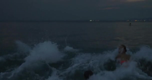 Familie mit Kind badet in der Dämmerung im Meer — Stockvideo