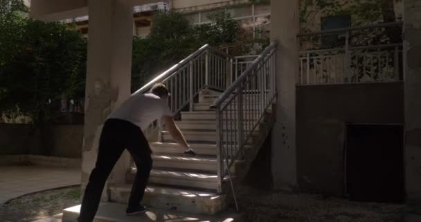 Мужчина отжимается на открытой лестнице — стоковое видео