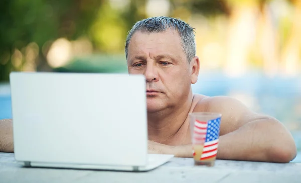 Adam dizüstü bilgisayar ve içecek yüzme havuzunda — Stok fotoğraf