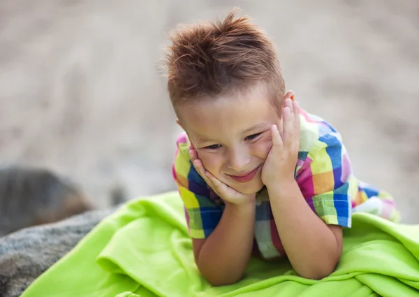 Niño con la cabeza en las manos en la manta de playa verde —  Fotos de Stock