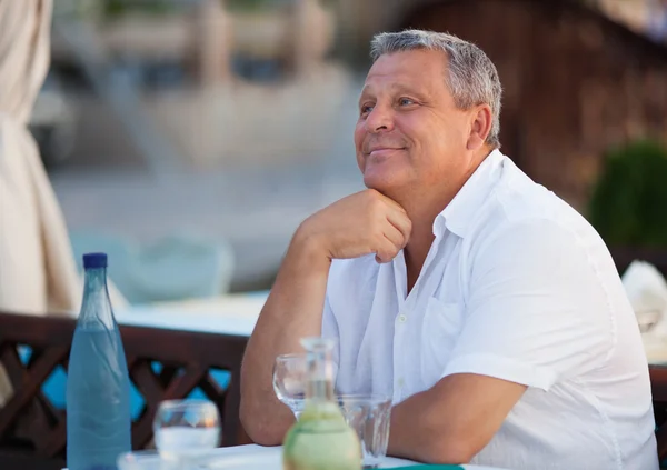 Smiling pensive middle-aged man at a restaurant — Stock Photo, Image