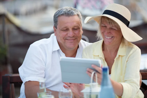 Couple d'âge moyen souriant utilisant une tablette — Photo