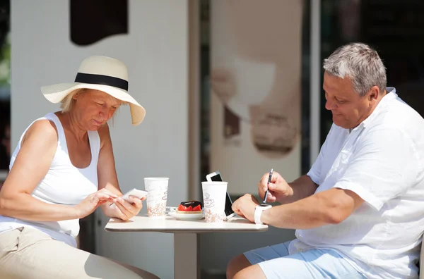 Couple sitting in cafe while using gadgets — Stock Photo, Image