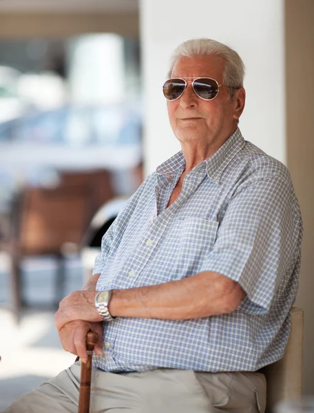 Senior man in sunglasses sitting waiting — Stock Photo, Image