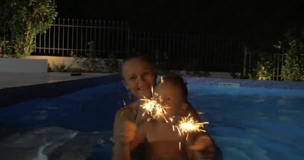 Donna e ragazzo con scintille in piscina — Video Stock