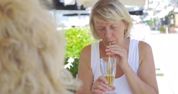 Пожилые женщины-друзья выпивают и разговаривают в кафе на открытом воздухе — стоковое видео