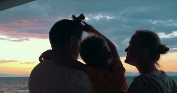 Счастливая семья с ребенком наслаждается закатом — стоковое видео