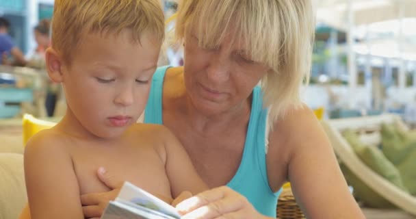 Femme mûre lisant un livre pour garçon — Video