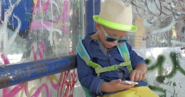 Garçon avec smartphone à l'arrêt de bus grungy ville — Video