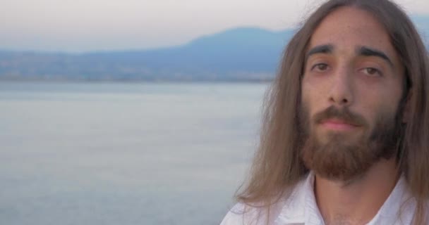 Homem de cabelos compridos com barba olhando para a câmera — Vídeo de Stock