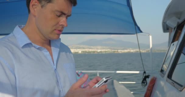 Hombre usando el teléfono inteligente en el yate — Vídeo de stock