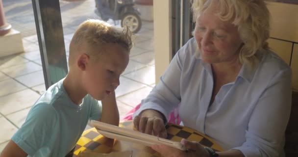Бабушка и внук с блокнотом в кафе — стоковое видео