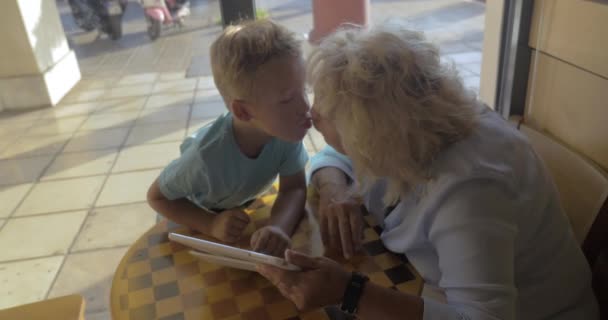 Niño y la abuela usando tableta PC en la cafetería — Vídeo de stock