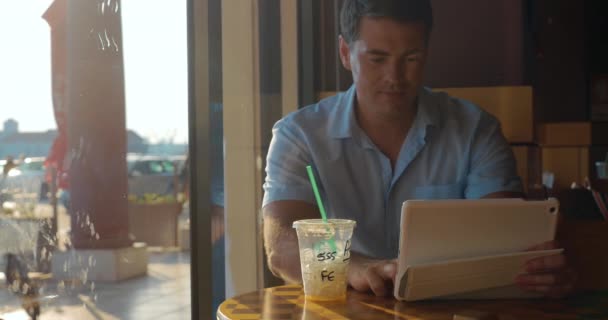 Человек с планшетным компьютером в кафе — стоковое видео