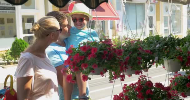 Padres e hijo mirando flores en la calle — Vídeo de stock