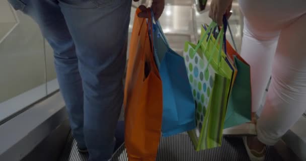 Casal com sacos de compras montando escada rolante — Vídeo de Stock