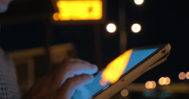 Man working with touch pad on bus stop at night — Stock Video