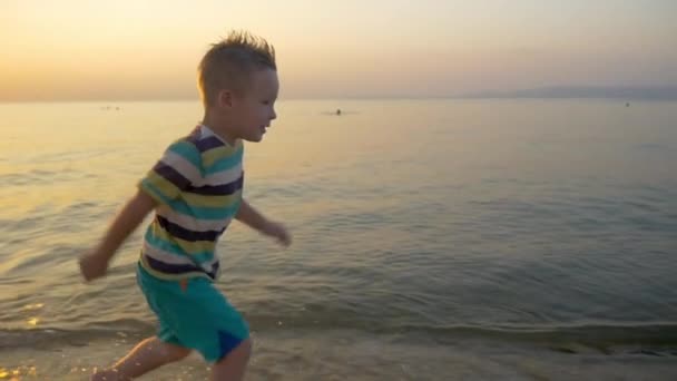 Lächelnder Junge läuft am Meer entlang — Stockvideo