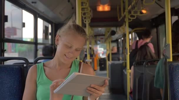 Mujer sonriente escribiendo en la tableta en el autobús — Vídeos de Stock