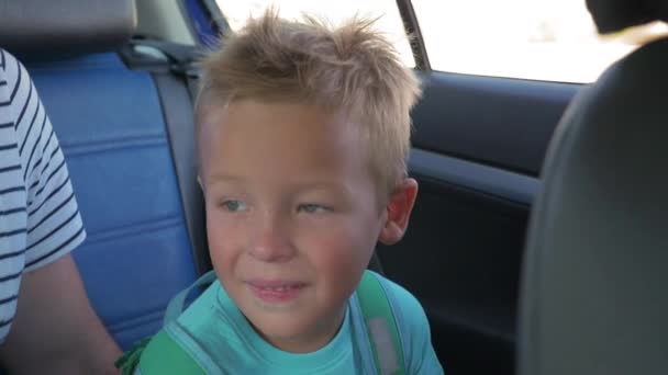 Smiling boy going by car on back seat — Stock Video