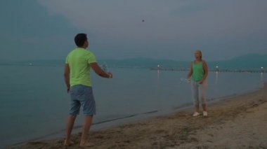 Erkek ve kadın üzerinde sahil badminton oynarken