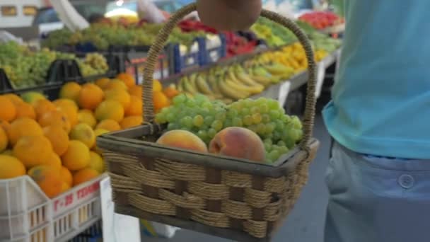 Homem com cesto de uvas e pêssegos no mercado de frutas — Vídeo de Stock