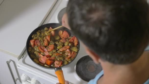Hombre guisando tomates, champiñones y papas en sartén — Vídeo de stock