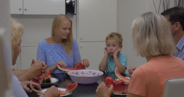 Семья с ребенком едят арбуз на кухне — стоковое видео