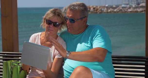 Casal sênior usando touch pad à beira-mar — Vídeo de Stock