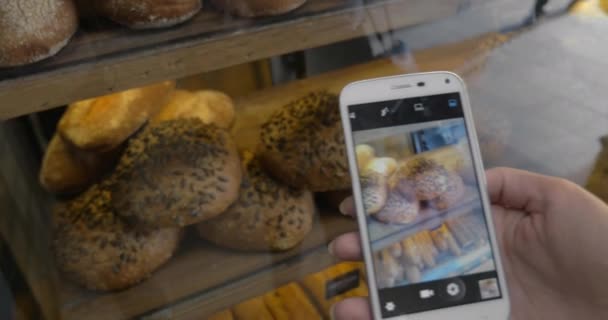 Vrouw met mobiele nemen schot van brood in de bakkerij — Stockvideo