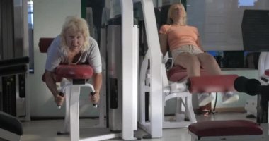 Kadın fitness makineleri üzerinde bacak egzersizleri yapıyor