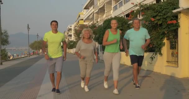Unga och äldre människor jogging i solnedgången — Stockvideo