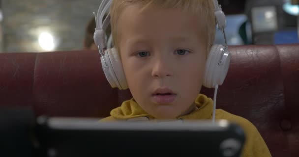 Niño en auriculares viendo dibujos animados en el teléfono inteligente — Vídeos de Stock