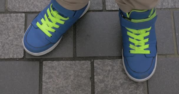 Kid feet in blue trainers on paved sidewalk — Stock Video