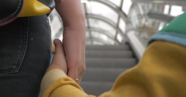 Madre e hijo tomados de la mano mientras monta escaleras mecánicas — Vídeo de stock