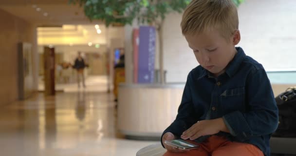 Niño volteando fotos en la celda en el centro de comercio — Vídeo de stock