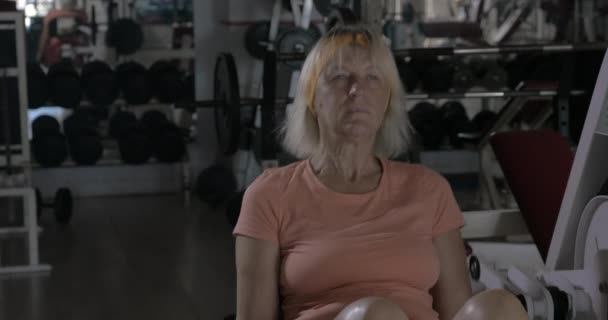 Mujer madura entrenando en la máquina de extensión de espalda — Vídeos de Stock