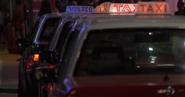 On road of night city ride taxi with flaming checker, in the background seen walking people — Stock Video