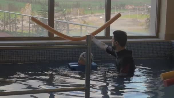 Реабилитационный центр Evexia, урок плавания, мальчик и учитель в бассейне — стоковое видео