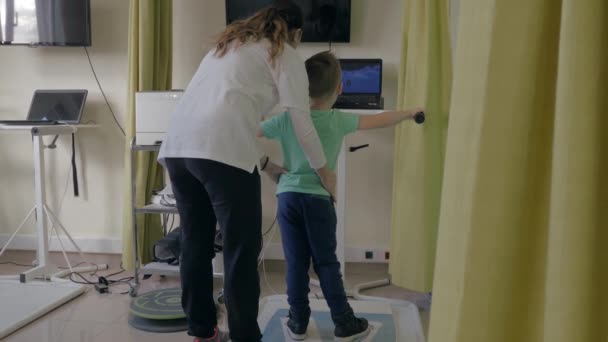 Centre de réadaptation Evexia, femme médecin examine petit garçon par un équipement spécial dans la salle de clinique — Video