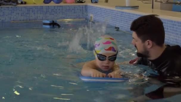 Centro de rehabilitación Evexia, lección de natación, niño pequeño y profesor en la piscina — Vídeos de Stock