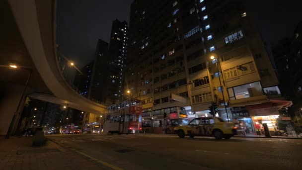 Vista de la ciudad nocturna y el edificio más alto con una carretera transitada con autobuses y coches de dos pisos — Vídeo de stock