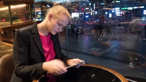 Снимок женщины, сидящей в кафе с помощью сенсорной панели на городском фоне. Сеул, Южная Корея — стоковое видео
